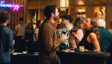 A group of people enjoying art and wine at Wine Walk at the Audain Art Museum.