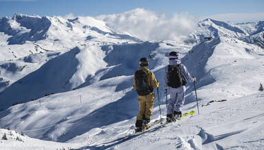 Two skiers looking down into Symphony from Sun Bowl on Whistler Mountain in Whistler, British Columbia.
