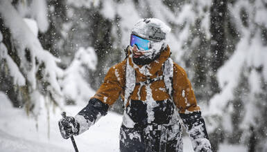 A skier covered in snow and smiling in Whistler