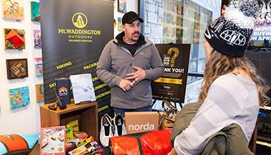 An outdoor exhibitor speaking with a festival attendee at a retail booth
