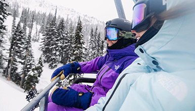 Two skiers riding on Big Red Express chairlift on Whistler Mountain