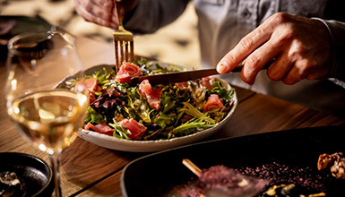 A person's hands digging into a spring salad at Balam restaurant in Whistler