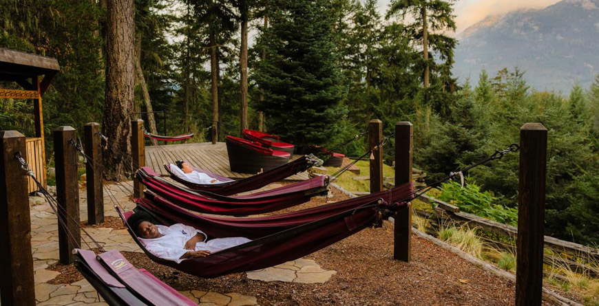 Two people relaxing in hammocks in the forest in Whistler, British Columbia