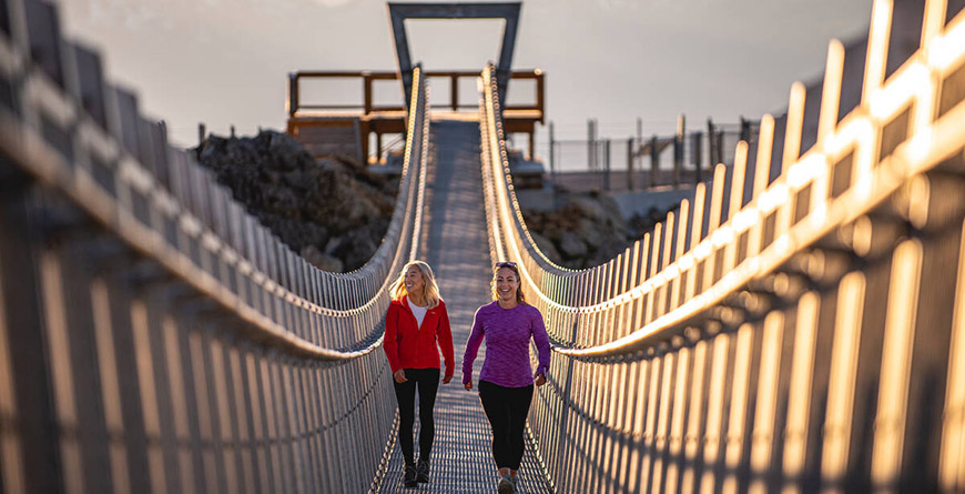 Two people walking across Cloudraker Skybridge at the top of Whistler Mountain