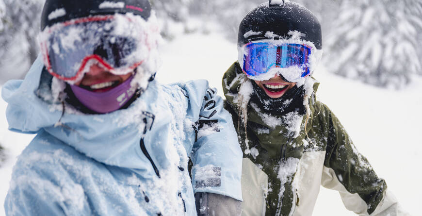 People covered in snow and laughing on the slopes at Whistler Blackcomb