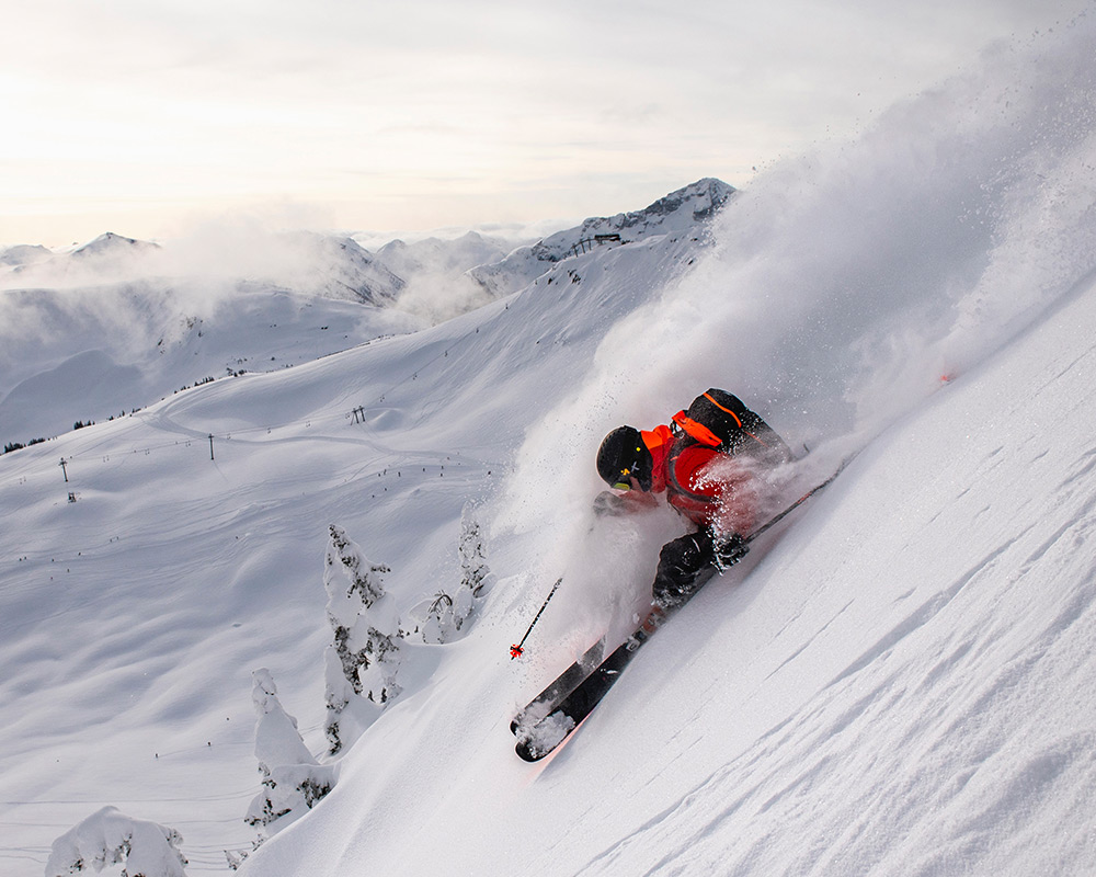 Skier carving deep powder on steep slope at Whistler Blackcomb.