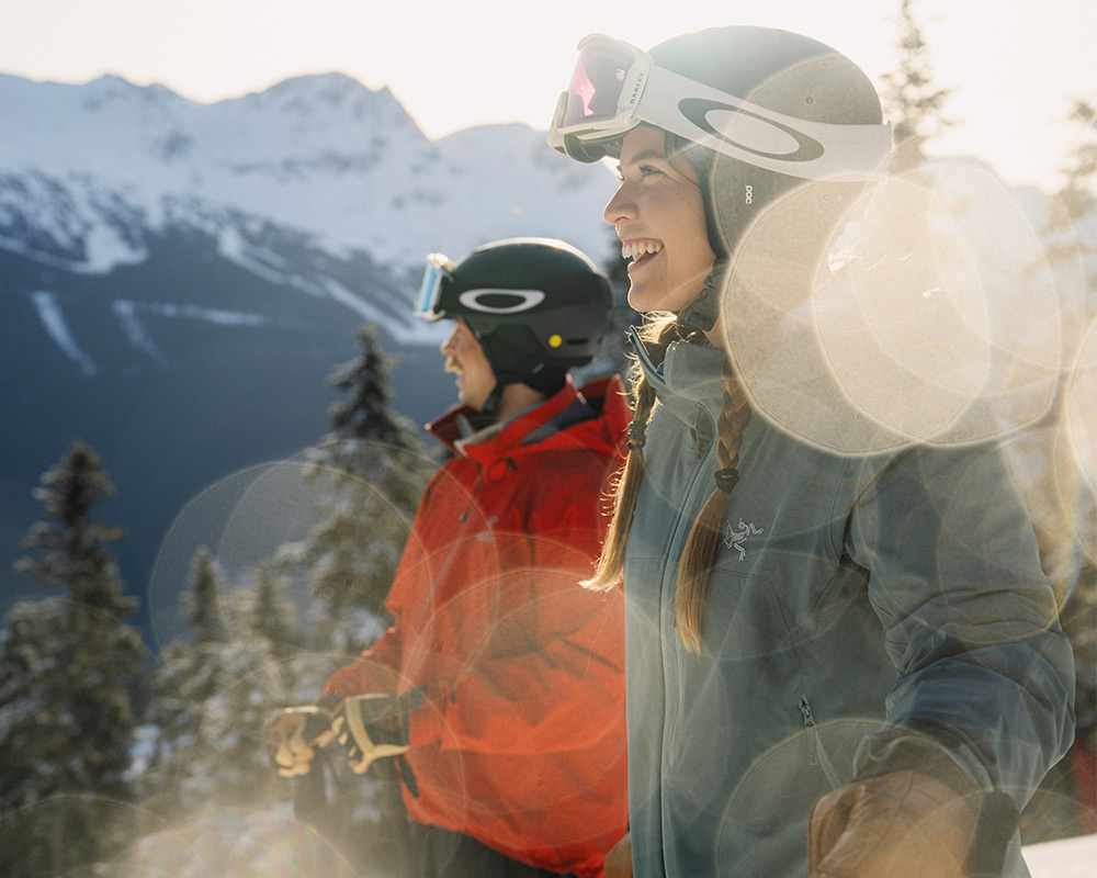 Smiling skiers enjoy sunny day on Whistler Blackcomb with mountain views.